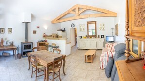 Una sala de estar acogedora con una mesa de madera, sillas, un sofá, un televisor y una chimenea.