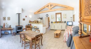 Ein gemütliches Wohnzimmer mit Holztisch, Stühlen, einer Couch, einem Fernseher und einem Kamin.