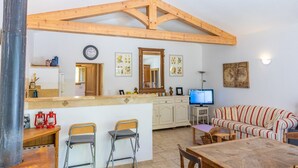 Una cocina con vigas de madera, un comedor con un sofá a rayas y un televisor.