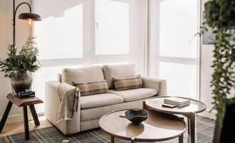 A living room with a sofa, two side tables, a floor lamp, and a potted plant.