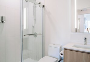 Ein modernes Badezimmer mit Duschkabine, Toilette und Waschbecken mit Spiegel darüber.