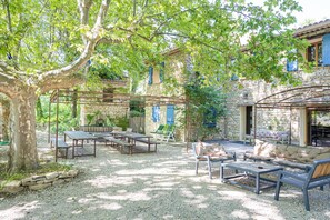 Une terrasse extérieure avec des murs en pierre, des meubles en bois et une pergola.