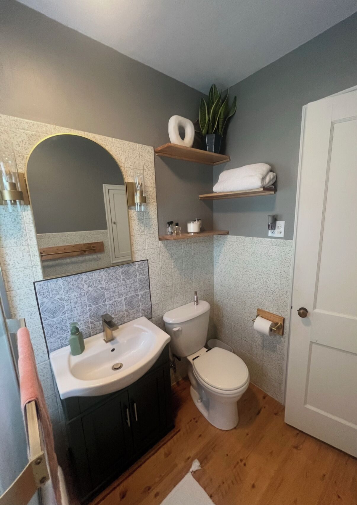 Un bany amb un lavabo, vàter i prestatges amb productes de tocador.