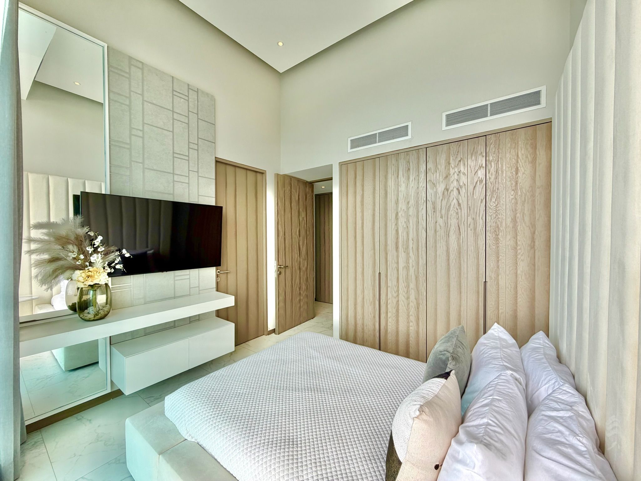 Une chambre à coucher moderne avec un grand lit, un téléviseur à écran plat et des armoires encastrées.