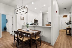 A modern kitchen with white cabinets, a microwave, and a hanging light fixture. - Lucaya Luxe At Bahama Bay (Davenport)