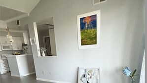 Un salón moderno con una mesa de centro negra, una planta en maceta y un cuadro en la pared.