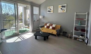 Ein modernes Wohnzimmer mit einer Couch, einem Couchtisch und einem Balkon mit Gartenmöbeln.