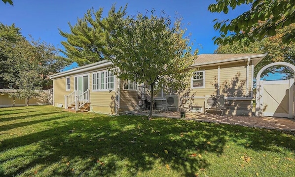 A single-story house with a front porch, a small tree, and a gated driveway.