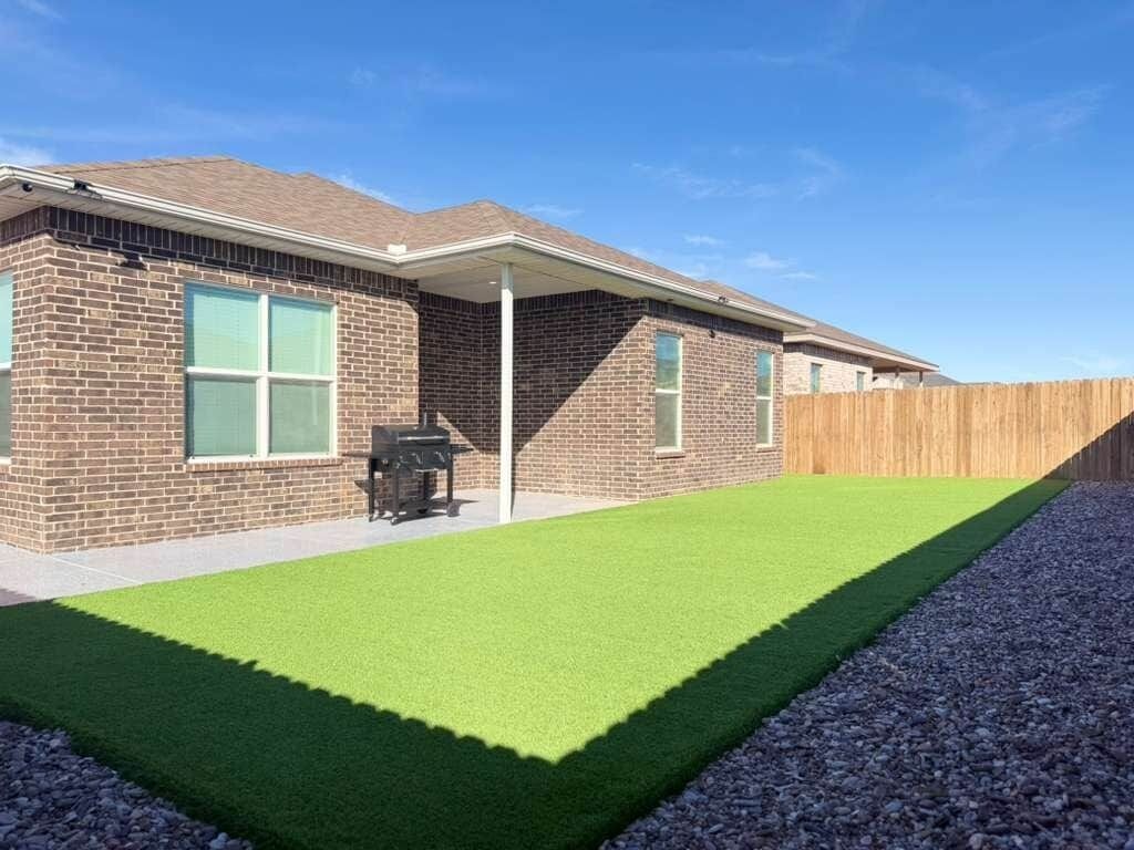 Une maison d’habitation dotée d’un patio couvert, d’une pelouse et d’une clôture en bois.