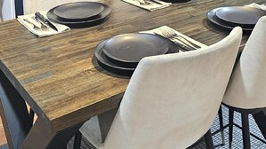 Una cucina moderna con zona pranzo, caratterizzata da un tavolo in legno, sedie bianche e forno integrato.