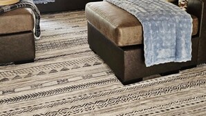 Un soggiorno con un divano in pelle marrone, un tappeto decorato e una coperta azzurra.