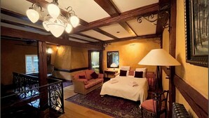 Ein gemütliches Zimmer mit Bett, Sofa, Schreibtisch und einer Chandelier.