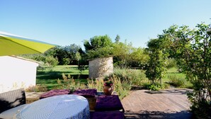 Une terrasse extérieure dotée d’une structure en pierre, d’une plateforme en bois et d’un parasol jaune.