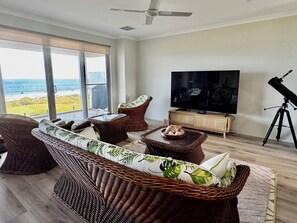 A living room with wicker furniture, a television, and a telescope. - The Sanctuary - Absolute ocean front
House sleeps 8. 4 bedrooms 2.5 bath (Dawesville)