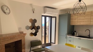A kitchen with a white table, a brick fireplace, and a view through a glass door. - Romantic Apartment in an Italian Village near Pollino National Park (Castelluccio Superiore)