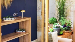 Quarto com parede azul-escuro, mesa consola de madeira com plantas, um espelho e um objeto decorativo na parede.