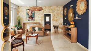 Sala de estar com sofá, mesa de centro e espelhos decorativos.