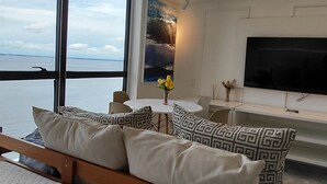 Una camera da letto moderna con una grande finestra, un letto, una TV e un'area pranzo.