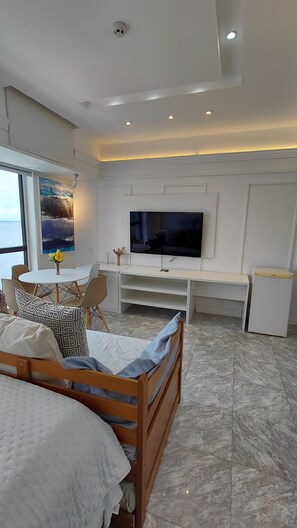 A modern bedroom with a bed, a TV, a dining area, and a view of the sea. - Tropical Executive Suíte Flat 817 Luxo (Manaus)