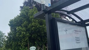 A bus stop shelter with a sign indicating a hospital nearby.