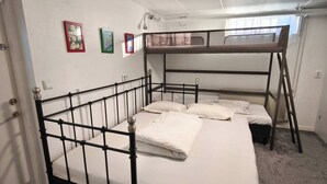 A bunk bed room with a white ceiling, a door, and a window.