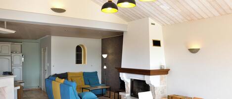 A spacious living area with a fireplace, a sofa set, and a dining table.