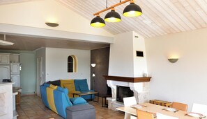A living room with a fireplace, a sofa, and a dining table. - Maison au calme 14km du puy du fou - 6chambres - 3SDB - extérieur - Linge inclus (Saint-Paul-en-Pareds)