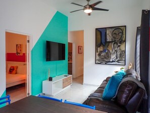 Ein modernes Wohnzimmer mit einer Couch, einem Fernseher und einem Gemälde an der Wand.