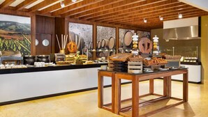 A breakfast buffet with wooden tables, a variety of food items, and a backdrop of wine barrels. - Villa La Valencia (San José del Cabo)