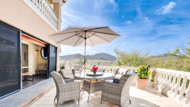 Eine Terrasse mit Korbmöbeln, einem Tisch und einem Sonnenschirm.