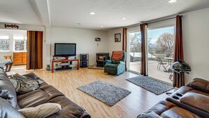 A living room with a leather sofa, a television, a fireplace, and a large window with curtains. - 18-Acre Working Farm w/ Mtn Views! Dolores Escape (Dolores)