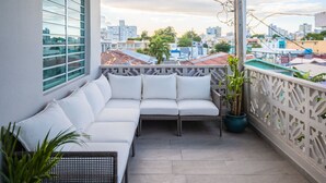 Een balkon met een witte bank, een potplant en uitzicht op de skyline.