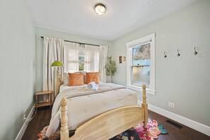 Ein Schlafzimmer mit Bett, Fenster, Lampe und Pflanze.