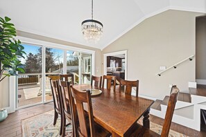 A dining area with a wooden table and chairs, a chandelier, and a view to a deck. - Walk to Beach Coeur d'Alene Retreat w/ Lake Views & BBQ Area (Coeur d'Alene)