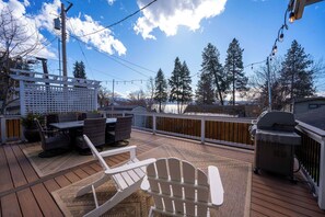 Eine Terrasse mit Gartenmöbeln, einem Grill und Blick auf BÀume und Berge.