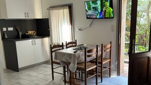 A compact living space with a dining area, kitchenette, and a TV mounted on the wall. - Relaxing under the olive trees (Santa-Reparata-di-Balagna)