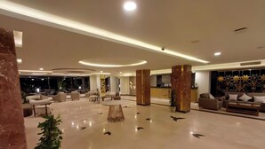 Un hall amplio con suelo de mármol, mobiliario moderno y una mesa de recepción.