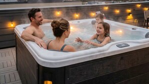 Ein Whirlpool mit Blick auf die Stadtlandschaft, eine Holzterrasse und Lichterketten.