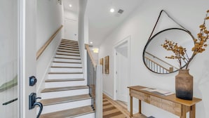 Eine Treppe mit Holzsitzstufen und Geländer, ein Konsolentisch mit einer Vase sowie ein an der Wand befestigter Spiegel.