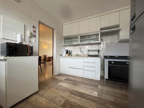 A modern kitchen with white cabinetry, a built-in oven, and a microwave. - Premium Location in Asa Sul | 3-Bedroom Apartment for up to 6 Guests (Brasília)