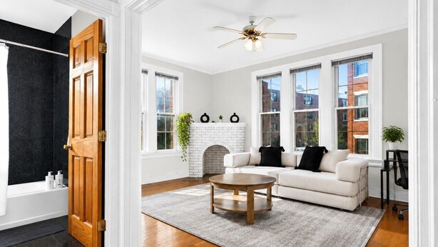 Uma sala de estar com lareira, um sofá branco, uma mesa de centro e vista para a cidade através de grandes janelas.
