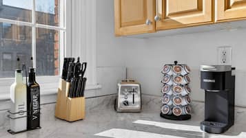 A kitchen with a toaster, a coffee maker, a knife block, and bottles on the counter.