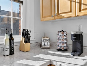 Una cocina con un tostador, una cafetera, un juego de cuchillos y botellas sobre la encimera.