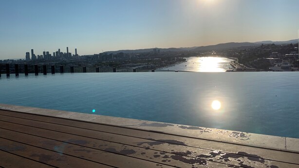 Una piscina frente al agua, con el horizonte de la ciudad al fondo.