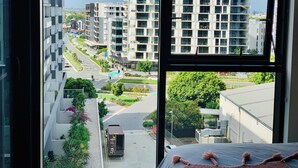 Un edificio moderno con varios pisos, balcones y vistas a una calle con zonas verdes y otros edificios.