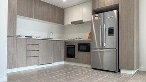 Una cocina moderna con refrigerador de acero inoxidable, horno empotrado y microondas.