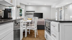 Uma cozinha moderna com armários brancos, uma área de refeições com mesa e cadeiras, e um forno embutido.