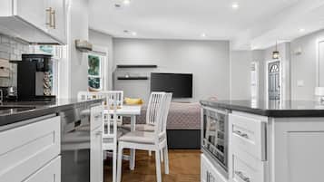 A modern kitchen with white cabinets, a dining area with a table and chairs, and a built-in oven.