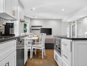 A modern kitchen with white cabinets, a dining area with a table and chairs, and a built-in oven. - Luxe 3 bd | Boston | Penthouse (Boston)