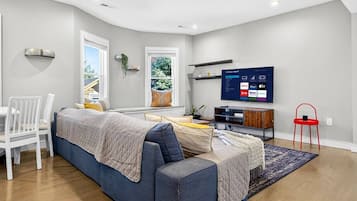 Ein modernes Wohnzimmer mit einer Couch, einem Esstisch mit Stühlen, einem Fernseher und einem roten Sessel.